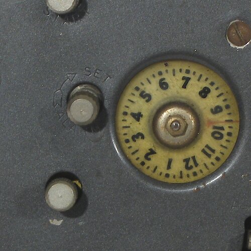 Plastic Transparent plastic dial with imprinted numerals, and the pointer is beneath it on a painted metal disc. Used starting late 1935 or early 1936.. Ben Bolt Plastic Alarm Dial