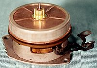 Side of the Sangamo motor showing the copper induction rotor which provides the starting and running torque. The copper rotor has a brass pinion which turns a fiber gear in the clock movement.